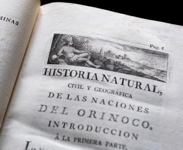 Detail of a printed book shows a decorative head piece on the title page written in Spanish.